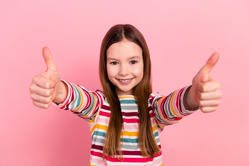 Photo of cute smile beautiful young girl kid double thumbs up gesturing recommend invite you kindergarten isolated on pink color background.