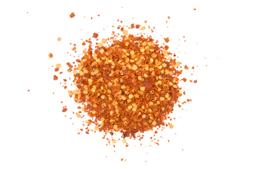Pile of red hot chili flakes isolated on a white background.