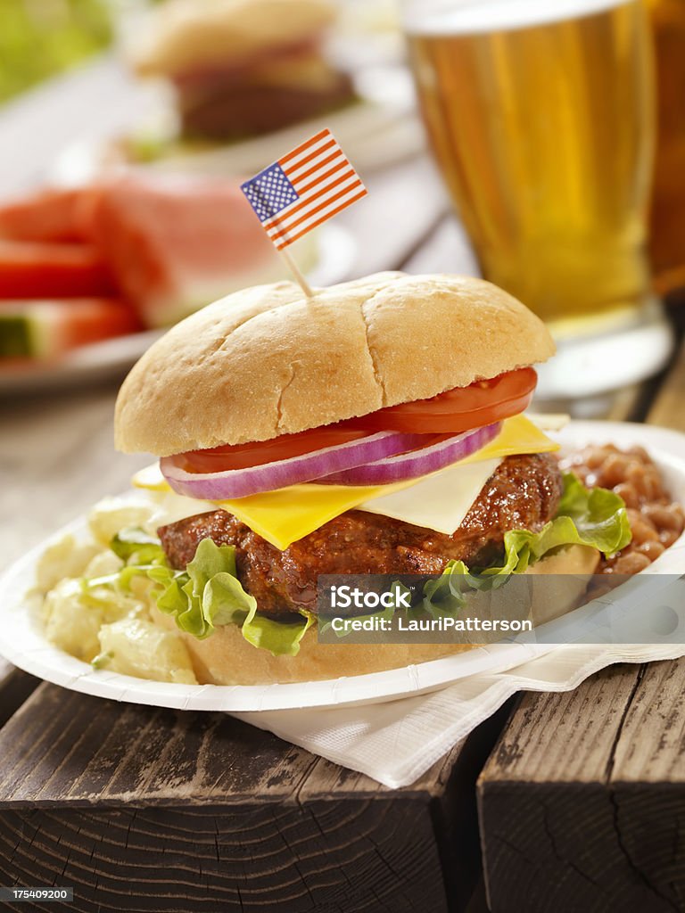 All American Cheeseburger and a Beer "BBQ Cheeseburger with Lettuce,Tomato and Red Onion with Potato Salad and Baked Beans at a 4th of July Picnic -Photographed on Hasselblad H3D2-39mb Camera" Alcohol - Drink Stock Photo