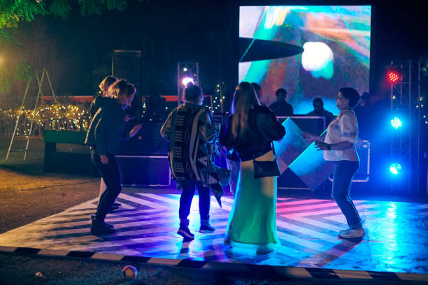 drôles de gens dansant la nuit sur la piste de danse en plein air avec fond de projecteurs multicolores - indian culture dancing dancer women photos et images de collection