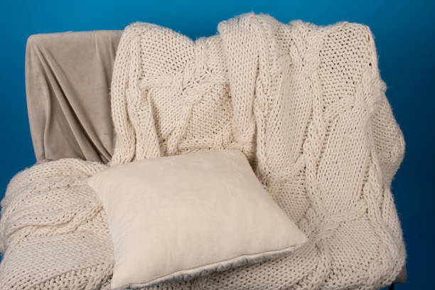 istock Beige knitted plaid and pillow on the sofa. 1754095777