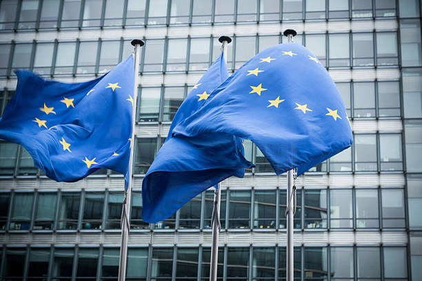 European flags. "European flags in front of the European Commission headquarters in Brussels, Belgium. ( Motion Blurred on flags)" european union currency stock pictures, royalty-free photos & images