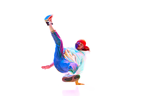 Man in his 30s, dancer in motion isolated over white studio background in neon light. Break dance. Concept of contemporary dance, street style, fashion, hobby, youth. Ad