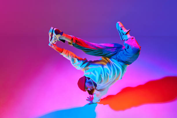istock Man in stylish sportswear in motion, dancing breakdance isolated over gradient studio background in neon light 1754099871