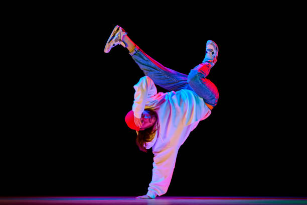 Flexible, artistic young man, breakdancer in motion, performing isolated over black studio background in neon light Flexible, artistic young man, breakdancer in motion, performing isolated over black studio background in neon light. Concept of contemporary dance, street style, fashion, hobby, youth. Ad contemporary dance stock pictures, royalty-free photos & images