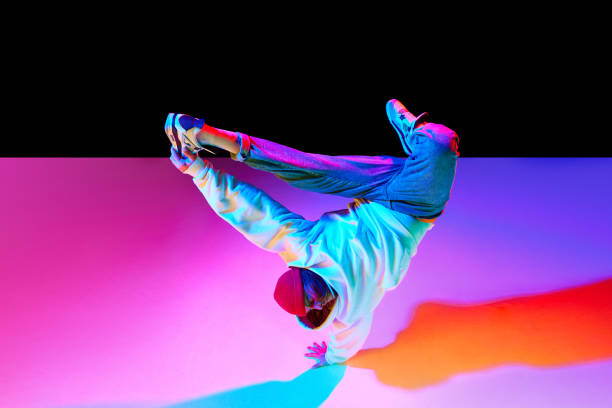 istock Athletic young man in motion, dancing breakdance isolated over black studio background in neon light 1754099876