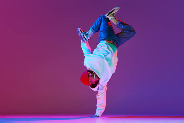 istock Man in stylish sportswear in motion, dancing breakdance isolated over gradient studio background in neon light 1754099881