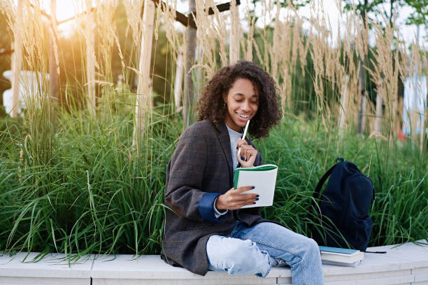 istock African american woman sitting on a bench and takes notes in a notebook 1754101066