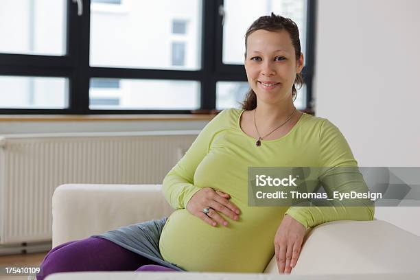 Happy Pregnant Woman Sitting On Sofa Stock Photo - Download Image Now - 25-29 Years, Adult, Adults Only