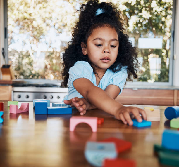 istock Girl, child and learning with building blocks in home for education, development and playing puzzle games for growth. Kid, play and toys for teaching creative skills and relax with educational game 1754103351