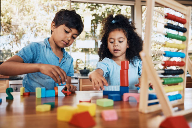 istock Siblings, children and playing building blocks for development, learning and growth on table in kitchen. Family, boy and girl child with toys for education, math, numbers and creativity in house 1754103354