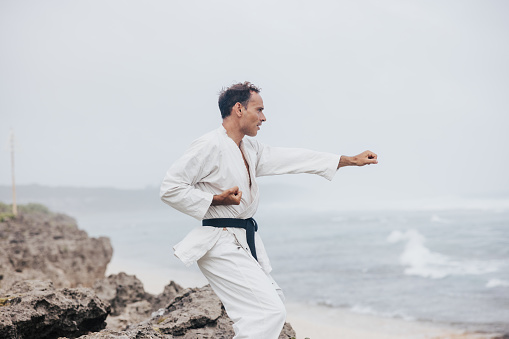 A karate enthusiast's demonstration on the beach combines strength and serenity, showcasing the beauty of martial arts in motion