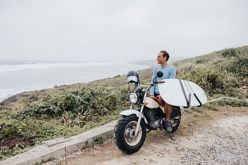 Surfer's arrival at the beach marks the beginning of a day of surf, with his motorcycle and surfboard ready.