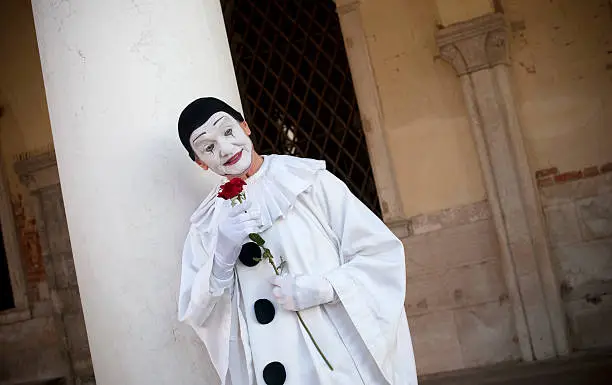 "Pierrot with red rose posing in front of Doges Palazze on Piazza San Marco in Venice, Italy."