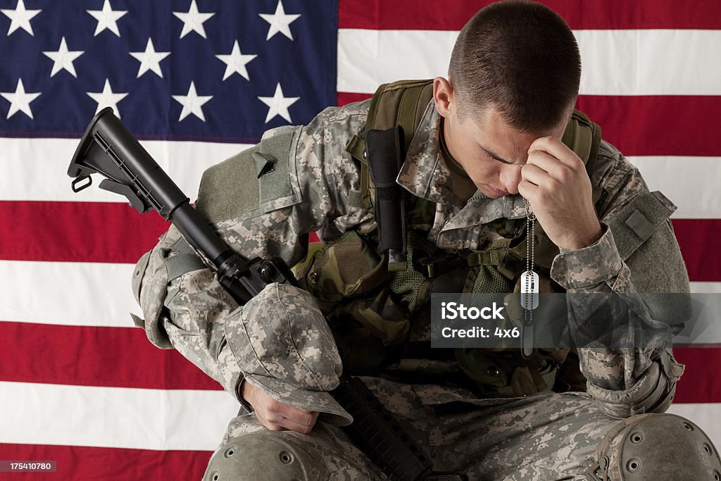 Army soldier sitting in front of American flag Army Soldier Stock Photo