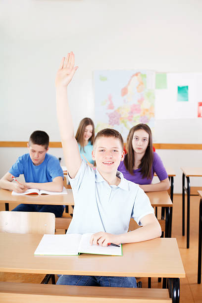 istock Schoolboy responding to teacher's question in classroom. 175411010