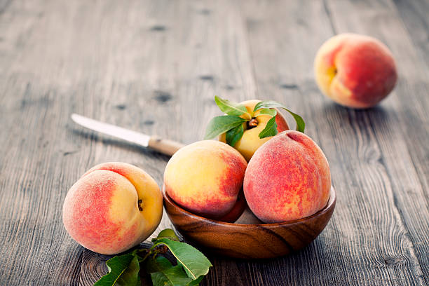 Peaches Fresh peaches in a bowl on wooden table peach photos stock pictures, royalty-free photos & images