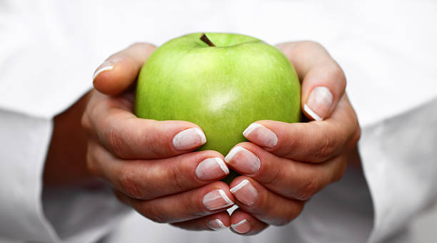 A woman with a manicure holding a green apple in her hands Green apple in hands health symbols/metaphors stock pictures, royalty-free photos & images