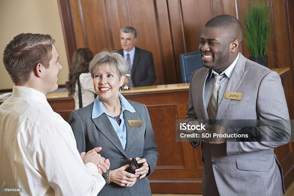 Hotel management trata de algo con huésped en el lobby - Foto de stock de Hotel libre de derechos