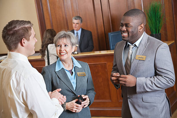Hotel management discussing something with guest in the lobby. 