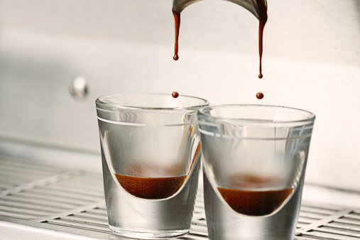 Close up action photo of a double shot espresso extraction into shot glasses.