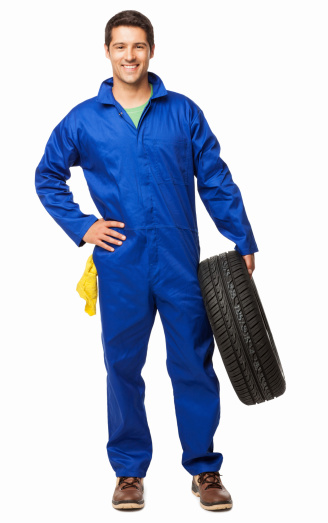 Full length portrait of an automotive technician holding a spare tyre. Vertical shot. Isolated on white.