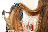 Woman hand brushing long hair with defocused mirror reflection, close up
