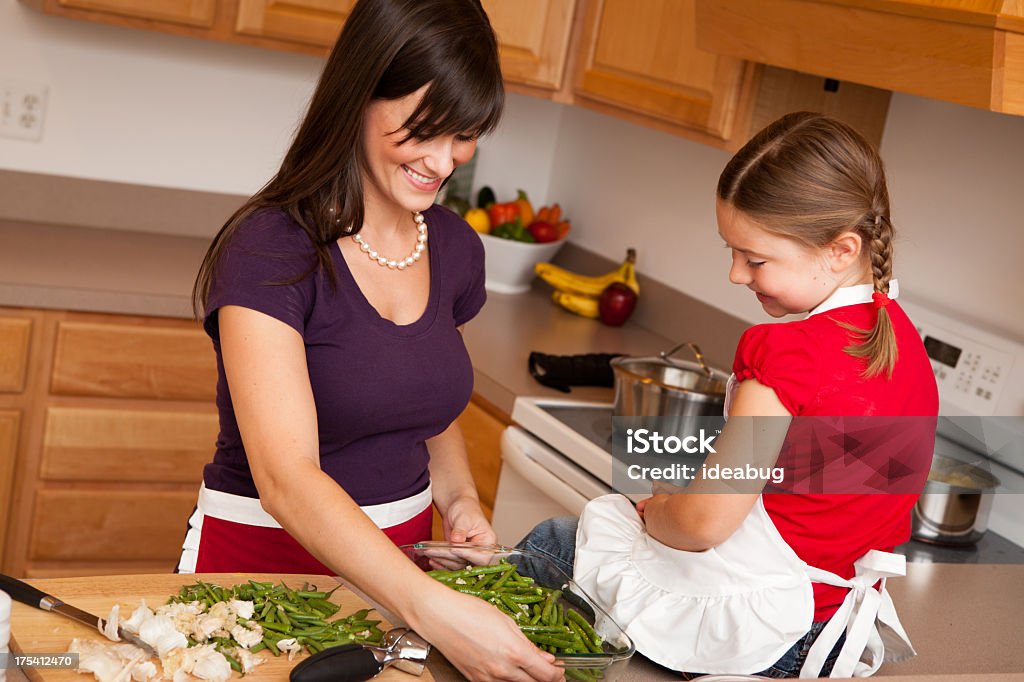 Happy Mother and Daughter Cooking Beans in Kitchen Color image of a happy, young mother and her daughter cooking green beans together in their kitchen at home. 20-29 Years Stock Photo