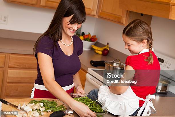 Happy Mother And Daughter Cooking Beans In Kitchen Stock Photo - Download Image Now - 20-29 Years, 25-29 Years, 6-7 Years