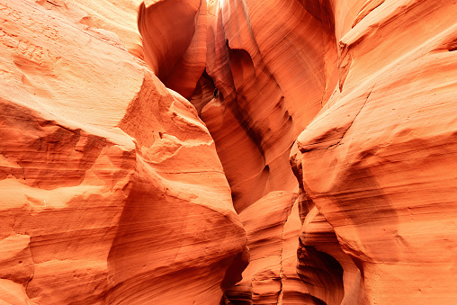 Nestled within the desert of Northern Arizona, Antelope Canyon exhibits the sheer beauty that nature can create. Famous for its lavish colors, unique patterns and complex textures, this slot canyon is a geological wonder that mesmerizes all who venture into its depths.  Carved into the red sandstone of the Navajo Nation, the canyon comes alive with a vibrant spectrum of reds, oranges, and yellows. The sunlight filtering through the narrow openings above casts an ever-changing, warm glow on the smooth, curving walls, creating a surreal play of shifting light and dancing shadows.  The rock formations within the canyon walls bear the unmistakable marks of time and weather. Millennia of wind and water erosion have sculpted the sandstone into flowing, sinuous shapes, creating a sensory experience that is as tactile as it is visual. Touching the canyon's surface connects a person directly to the forces of wind and water that have shaped it over countless millennia.  Antelope Canyon is in Coconino County near Page, Arizona, USA.