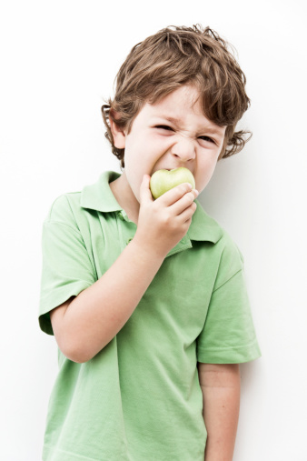 A little boy is eating a green apple eagerly