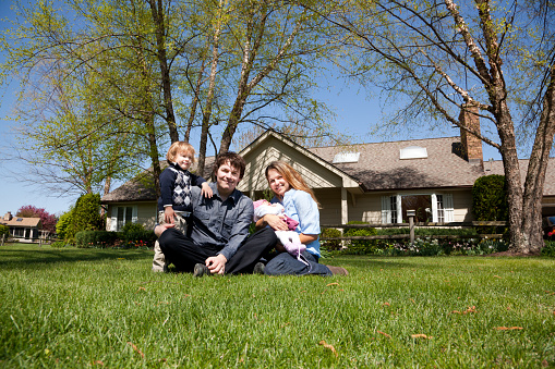 Young family with two children in front of house