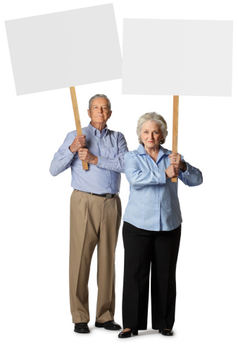 Striking or protesting senior woman and man holding a blank sign.