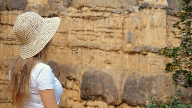 istock Woman stands on cliff edge, looking at vast canyon and mountain range below 1754135562