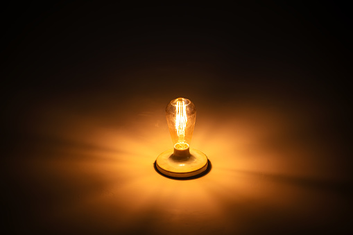 Classic light bulb glowing in the dark