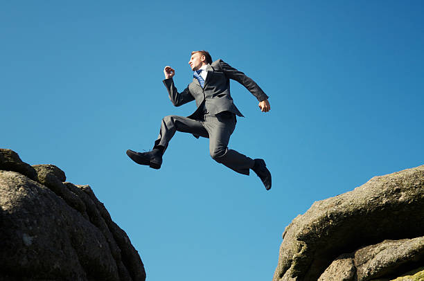 homem de terno saltar entre serras altas não rocks - fiscal cliff imagens e fotografias de stock