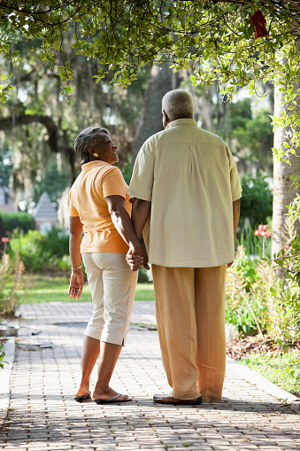 Senior African American couple holding hands, on a walk in a park.