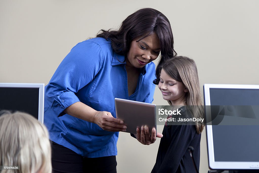 Teacher with Tablet Computer "A teacher in a classroom, instructing students using a handheld tablet computer." 40-44 Years Stock Photo