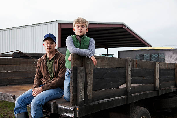 agricoltore e figlio seduto sul retro del camion - farmer farm family son foto e immagini stock