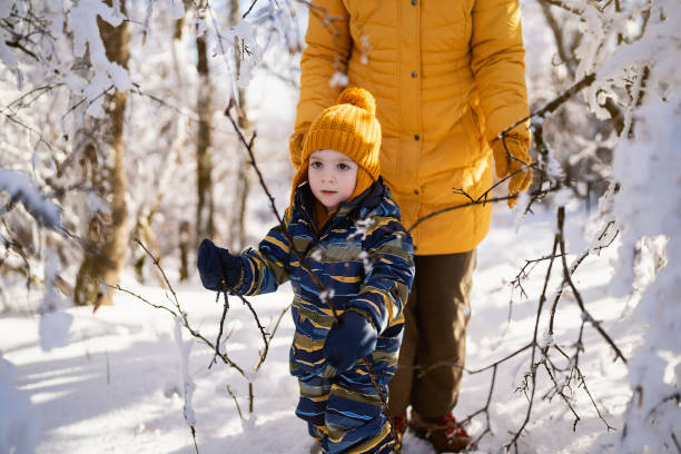 istock Little boy enjoying a walk through a snowy forest with his mom 1754150484