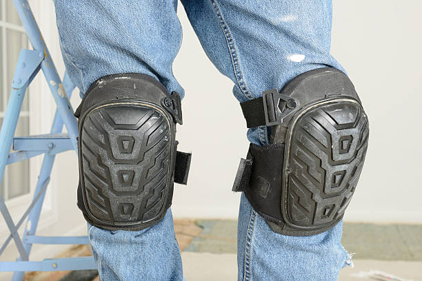 Man's Legs With Kneepads In Room Under Renovation "Protective kneepads on a man's legs, with a room under renovation in the background." kneepad stock pictures, royalty-free photos & images