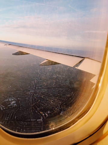 Photo taken from the window of an airplane showing a wing and also a  sky view of London