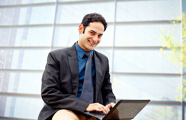 elegante empresário asiático usando computador portátil em frente do edifício de escritórios - male asian ethnicity manager expressing positivity imagens e fotografias de stock