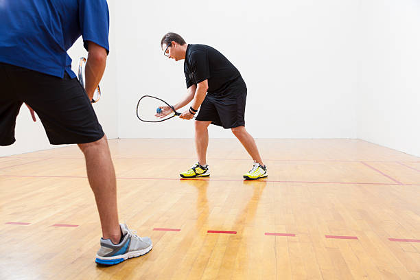 Racquetball Two men playing racquetball on court. One serving. racketball stock pictures, royalty-free photos & images
