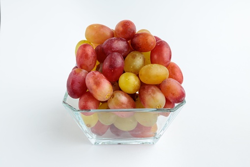 A bowl filled with bright, juicy grapes on a white background