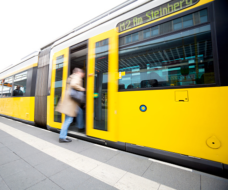 Person stepping onto yellow tram in Berlin, Germany. blurred motion.
