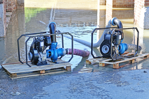 Two Petrol Engine Pumps at Cargo Pallets Pumping Out water From Flooded Passage