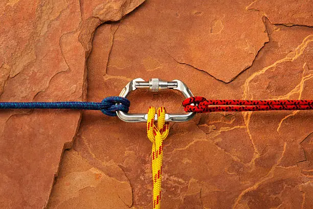 "This is a close-up of three tight rock climbing ropes attached to a carabiner clip against a red rock background. This image can symbolize teamwork, connectivity, relationships, etc.Click on the links below to view lightboxes."