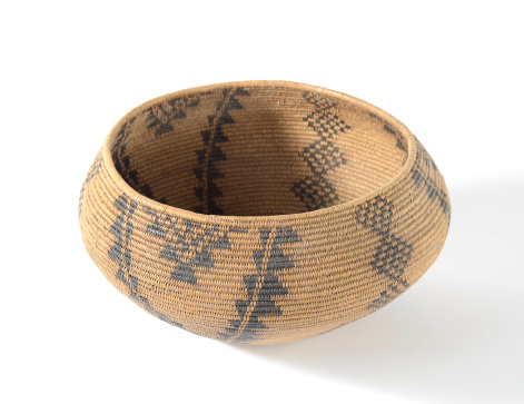 Antique Native American woven basket on a white background.