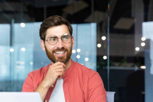 istock Smiling dreamy businessman inside office at workplace, experienced and successful programmer engineer smiling and looking out window, satisfied with results of achievement at work 1754201039